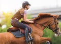 Young pretty girl riding a horse with backlit leaves behind in s