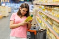 Young pretty girl is shopping in a big store. Beautiful smiling young woman in casual clothes is holding two bottles of olive oil Royalty Free Stock Photo