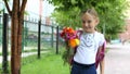 Young pretty girl standing near school with backpack and flowers sunny day. Back to school. Schoolgirl go to study. Girl Royalty Free Stock Photo
