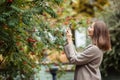 Young pretty girl tourist taking pictures of autumn trees in the park in autumn, copy space Royalty Free Stock Photo