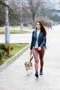 Young pretty girl walking her cute dog in the park. The girl actively spends her leisure Royalty Free Stock Photo