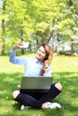 Young pretty girl working on laptop outdoor, lying on grass, caucasian 20 years old Royalty Free Stock Photo