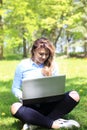 Young pretty girl working on laptop outdoor, lying on grass, caucasian 20 years old Royalty Free Stock Photo