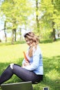 Young pretty girl working on laptop outdoor, lying on grass, caucasian 20 years old Royalty Free Stock Photo