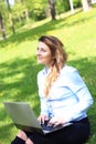 Young pretty girl working on laptop outdoor, lying on grass, caucasian 20 years old Royalty Free Stock Photo