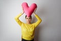 Young pretty girl in yellow tshirt holding big plush red heart over empty white background. Royalty Free Stock Photo