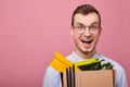 Happy guy in a sky blue shirt and glassesholds cardboard box with things in his hands Royalty Free Stock Photo