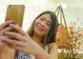 Young pretty and happy Asian Korean tourist woman smiling holding mobile phone taking self portrait selfie picture outdoors in bea Royalty Free Stock Photo