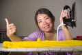 Young pretty and happy Asian Korean woman using iron at home kitchen ironing clothes smiling cheerful and carefree enjoying domest Royalty Free Stock Photo