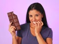 Young pretty and happy hispanic woman holding chocolate bar with teeth bite smiling in sugar and sweet addiction concept Royalty Free Stock Photo