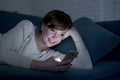 Young pretty and happy red hair woman on her 20s or 30s lying on home couch or bed using mobile phone late at night smiling relaxe Royalty Free Stock Photo