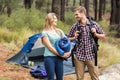 Young pretty hiker couple holding a sleeping bag and backpack