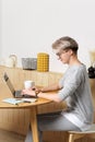 Young pretty hipster millennial female working with laptop in cafe interior, side view