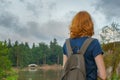 Young pretty lady with backpack walking outdoors in summer evening. Tourist on the beautiful landscape background. Monrepos Park, Royalty Free Stock Photo