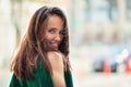 Young pretty likable cheerful woman posing summer city outdoor. Beautiful self-confident girl dressed in emerald-colored jumpsuit