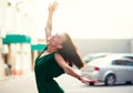 Young pretty likable cheerful woman posing summer city outdoor. Beautiful self-confident girl dressed in emerald-colored jumpsuit