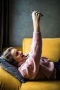 Young pretty woman lying on her back on sofa making selfie on her phone Royalty Free Stock Photo