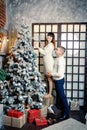 Young pretty man in white sweater and woman in knitted dress decorate tree