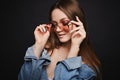 Young model woman in cool pink sunglasses and denim jacket posing on black isolated background. Attractive girl with Royalty Free Stock Photo