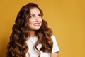 Young pretty model woman with natural makeup and brown curly hair looking up on yellow background. Pretty female smiling Royalty Free Stock Photo
