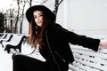 Young pretty modern hipster girl waiting on bench at winter snow park alone, lifestyle people concept Royalty Free Stock Photo