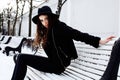 Young pretty modern hipster girl waiting on bench at winter snow park alone, lifestyle people concept Royalty Free Stock Photo