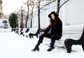 Young pretty modern hipster girl waiting on bench at winter snow park alone, lifestyle people concept Royalty Free Stock Photo