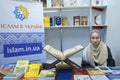 Young pretty muslim girl presents islamic books in the bookshop, Quran placed on the counter