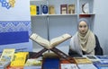 Young pretty muslim girl presents islamic books in the bookshop, Quran placed on the counter