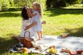 young pretty pregnant brunette woman having fun with her daughter on picnic on green grass in park, lifestyle people