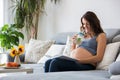 Young pretty pregnant woman reading book at home on the couch Royalty Free Stock Photo