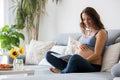 Young pretty pregnant woman reading book at home on the couch Royalty Free Stock Photo