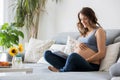 Young pretty pregnant woman reading book at home on the couch Royalty Free Stock Photo