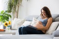 Young pretty pregnant woman reading book at home on the couch Royalty Free Stock Photo