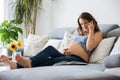 Young pretty pregnant woman speaking on the phone at home on the Royalty Free Stock Photo