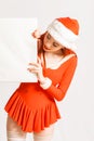 Young and pretty red head girl in a Santa Claus mini dress on a neutral white backgroung