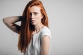 Young pretty redhead girl with freckles looking at camera smiling touching hair Royalty Free Stock Photo