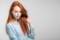 Young pretty redhead girl with freckles looking at camera smiling touching hair Royalty Free Stock Photo