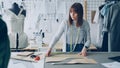 Young pretty seamstress is measuring clothing patterns with tape-measure in her modern tailor's shop. Getting ready Royalty Free Stock Photo