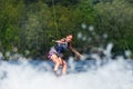 Young pretty slim brunette woman riding wakeboard on wave of mot Royalty Free Stock Photo