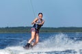 Young pretty slim brunette woman riding wakeboard on wave of motorboat in summer lake Royalty Free Stock Photo