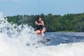 Young pretty slim brunette woman riding wakeboard on wave of motorboat in summer lake Royalty Free Stock Photo