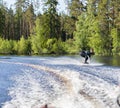 Young pretty slim brunette woman in wetsuit riding wakeboard on wave of motorboat Royalty Free Stock Photo