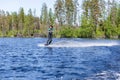 Young pretty slim brunette woman in wetsuit riding wakeboard on wave of motorboat Royalty Free Stock Photo