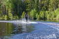 Young pretty slim brunette woman in wetsuit riding wakeboard wave of motorboat Royalty Free Stock Photo