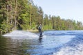 Young pretty slim brunette woman in wetsuit riding wakeboard wave of motorboat Royalty Free Stock Photo