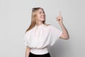 Young pretty smiling blonde girl in black skirt isolated on white background points finger up. Place for text, copyspace Royalty Free Stock Photo