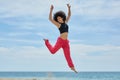 Young pretty sportswoman jumping on beach raising hands Royalty Free Stock Photo