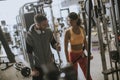 Young sporty woman working out on pull-down machine in gym with personal trainer Royalty Free Stock Photo