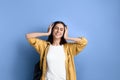 Young pretty student girl is enjoying music, listening to favorite band in headphones, touches head with hands, dancing, living Royalty Free Stock Photo